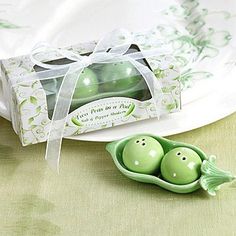 two peas in a pea pod shaped container next to a white plate and napkin on a table