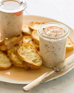 a plate topped with bread slices next to a jar of dip