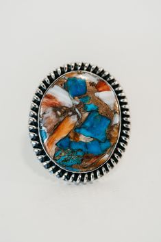 an image of a ring with blue and orange stones in it on a white surface