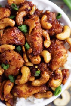 a white bowl filled with cashews on top of rice and garnished with cilantro