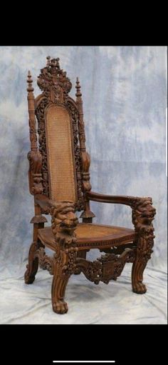 an ornate carved wooden chair with caned arms and back rests against a gray backdrop