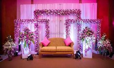 a couch sitting in front of a stage decorated with flowers