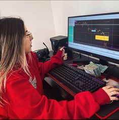 a woman sitting in front of a computer monitor with money on the desk next to her