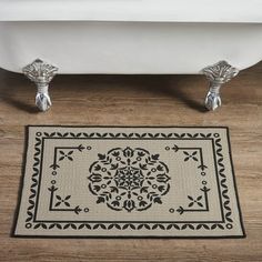 a bath tub sitting next to a rug on top of a wooden floor