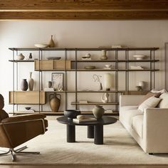 a living room filled with lots of furniture next to a wall mounted book shelf full of vases