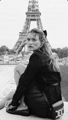 a woman sitting on the ground in front of the eiffel tower