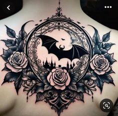 the back of a woman's shoulder with a bat and roses tattoo on it