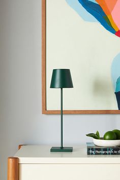 a green lamp sitting on top of a white dresser