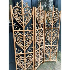 a set of three decorative iron screens with hearts and scrolls on them, sitting in front of a door