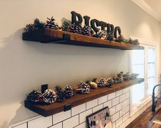 two wooden shelves filled with pine cones on top of a white tiled wall next to a window