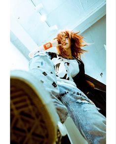 a woman with red hair laying on the floor next to a pair of jeans and sneakers