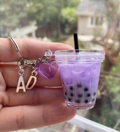 a hand holding a purple drink and a keychain with the letter d on it