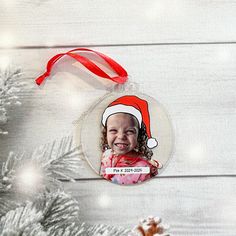 a christmas ornament hanging from a tree with a red ribbon around it's neck