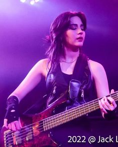 a woman playing a guitar on stage with purple lighting behind her and the caption reads, 2012 @ jack lee