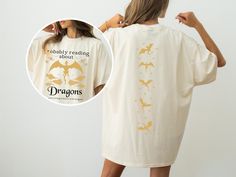 a woman is wearing a white shirt with gold dragon designs on it and has her back turned to the camera