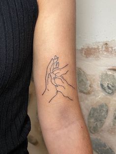 a woman with a tattoo on her arm holding the hand of another person's wrist