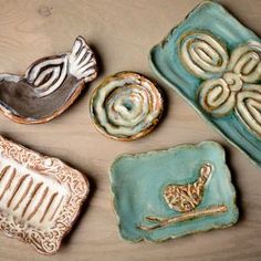 four decorative ceramic dishes sitting on top of a wooden table