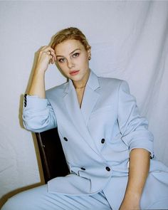 a woman sitting in a chair wearing a blue suit