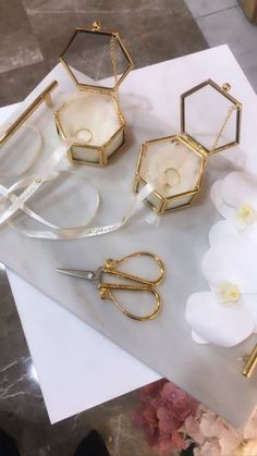 several pieces of jewelry sitting on top of a piece of paper next to some flowers