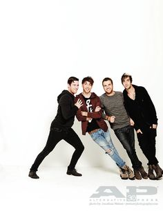 four young men posing for a photo in front of a white background with one holding his arm around the other