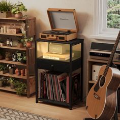 a record player sitting on top of a shelf next to a guitar