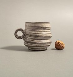 a ceramic cup with a handle next to a small round object on a table top