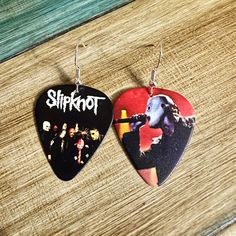 two guitar picks with the words slipknot on them sitting on a wooden surface