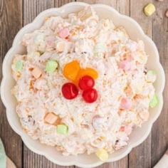 a white bowl filled with cereal and candy candies on top of a wooden table