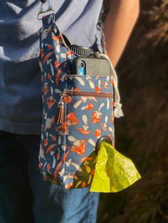 a woman holding a cell phone in her hand with a yellow bag attached to it