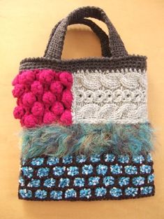 a crocheted bag with flowers and feathers on the handle is hanging from a wall