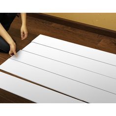 a person is cutting out some white paper on the floor with a pair of scissors