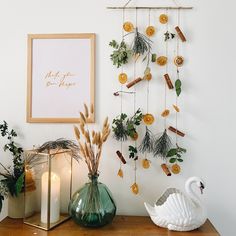 a wooden table topped with vases filled with flowers and greenery next to a white wall