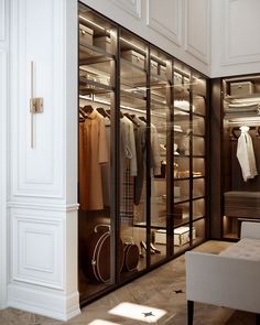 a walk in closet filled with lots of clothes and bags next to a white bench