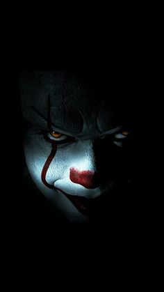 a creepy clown with glowing eyes and red nose in the dark, looking at the camera