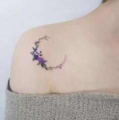 a woman's upper arm with purple flowers on the left side of her shoulder