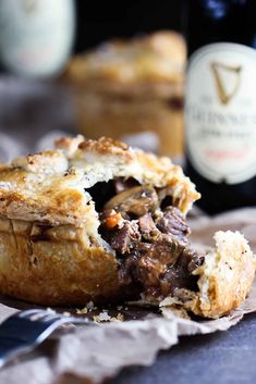 a piece of meat pie sitting on top of a table next to a bottle of wine