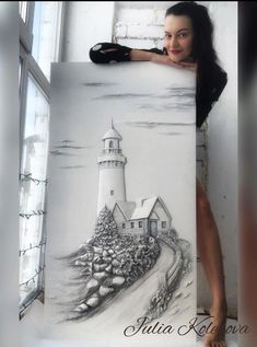 a woman holding up a drawing of a lighthouse