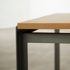 a close up of a wooden table with metal legs and a wood top on concrete floor