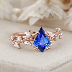 a blue ring sitting on top of a white flowered cloth next to a bouquet of flowers