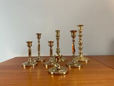 six brass candlesticks sitting on top of a wooden table