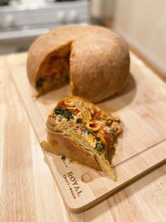 a wooden cutting board topped with a slice of pizza next to a loaf of bread