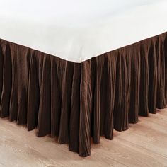 the bed is made with brown pleated bedskirt