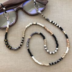 Best selling glasses chain! This eyeglasses chain is made with black, white, neutral and gold beading. Add a FREE PERSONALIZATION to make it yours or a special gift. Securely holds your sunglasses, readers, or mask in style or connect the ends to wear as a necklace. See shop for many other color patterns to choose from. Beading and patterns vary as no 2 chains are alike!  Size: 27"  Made in Las Vegas. Visit our other store: MADELV.com  FALAB POLICY & SHIPPING  ALL SALES FINAL. We do not accept returns especially on personalized items so please make sure you read listing carefully regarding size, color, etc and message us with questions before ordering or custom orders. We stand by our products and strive for customer satisfaction. If there is ever an issue we always encourage our customers Trendy Black Glasses Chains For Gift, Summer Gift Black Glasses Chains, Trendy Black Beaded Glasses Chains, Trendy Black Glasses Chains For Everyday, Black Beaded Glasses Chains As Fashion Accessory, Black Beaded Glasses Chains For Fashion, Black Beaded Glasses Chains As Gift, Black Round Beads Glasses Chains As Gift, Black Beaded Glasses Chains For Gift