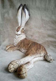 a statue of a rabbit laying on its side with it's legs spread out