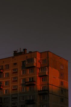 an orange building is lit up by the sun's rays in the dark sky