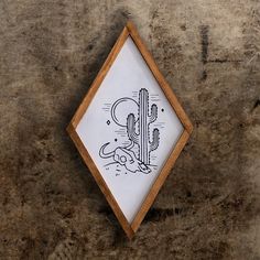 a drawing in a wooden frame with a cactus on it