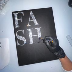 a person writing the word fash on a black board with white letters and glitters