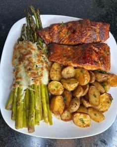 a white plate topped with meat, potatoes and asparagus