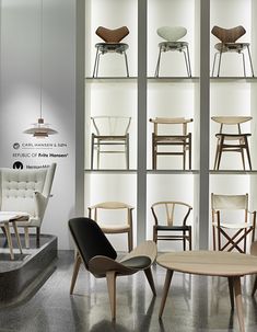 several chairs and tables in a room with glass shelves on the wall behind them that are displaying different types of furniture