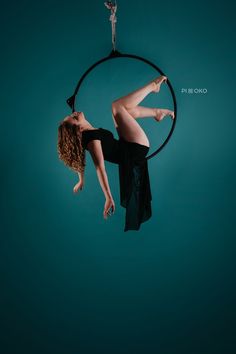 a woman is hanging upside down on a hoop